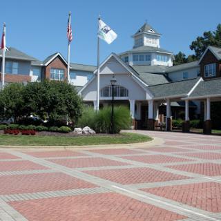 A scenic view of a hotel entrance featuring a brick pathway and flags under a clear blue sky.