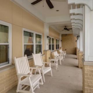 A peaceful porch with rocking chairs and ceiling fans under a covered patio.