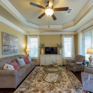 A cozy living room with a sofa, armchairs, and a large rug, featuring warm lighting and decorative elements.