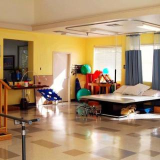 A well-equipped physical therapy room with various exercise tools and a therapy bed.