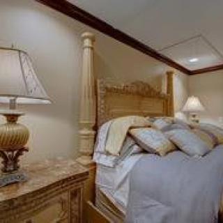 A cozy bedroom with a wooden bed, plush pillows, and bedside lamps.