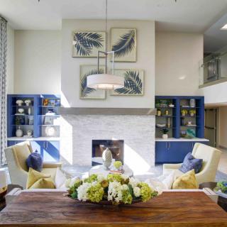 A modern living room with a stylish fireplace, comfortable seating, and elegant decor featuring artwork and a floral arrangement.