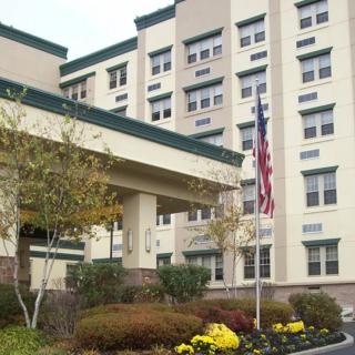 A multi-story hospital building with well-maintained landscaping and an American flag at the entrance.