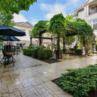 A beautifully landscaped patio area with a pergola, outdoor furniture, and lush greenery.