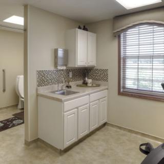 A well-lit bathroom with a sink, cabinet, and window, featuring a tile backsplash.
