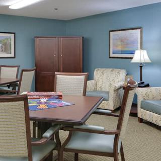 A cozy living room with a table, chairs, cabinet, and decorative paintings.