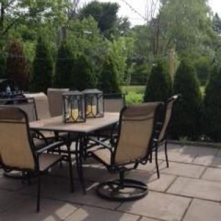 A cozy outdoor patio with a table and chairs surrounded by greenery.