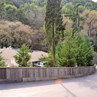 A suburban house surrounded by trees and a wooden fence, nestled in a forested area.