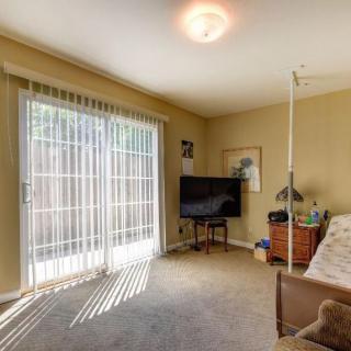 A cozy bedroom with a TV, bed, and large sliding glass doors covered by vertical blinds.