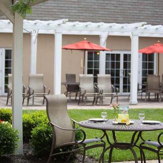 A cozy outdoor patio with a table set for drinks and chairs under red umbrellas.