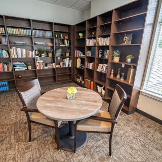 A cozy library reading area with bookshelves and a round table.
