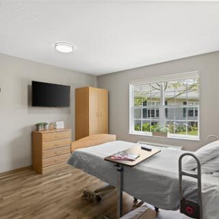 A serene hospital patient room featuring a bedside table, window with a view, and modern furnishings.