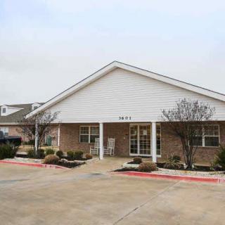 A suburban single-story brick building with a driveway and small shrubs.