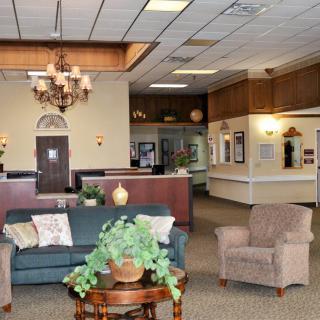 A comfortable and well-decorated lobby area with sofas, chairs, a chandelier, and a reception desk.