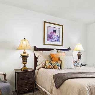 A cozy bedroom with elegant lamps and decorative pillows.