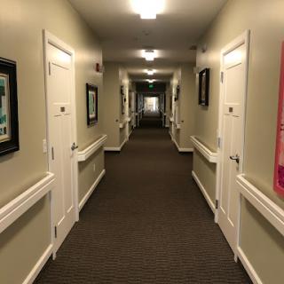 A well-lit hallway featuring multiple doors and framed pictures along the walls.