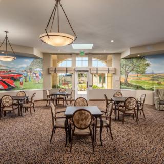 A cozy dining area with multiple tables and chairs, decorated with murals on the walls and illuminated by ceiling lights.