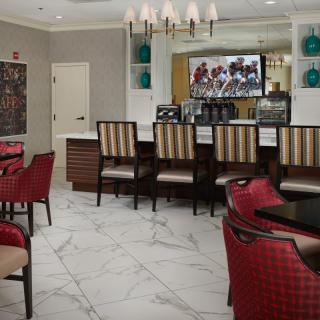 A modern dining area with upholstered chairs, a bar counter, and a television.