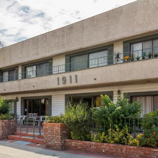 A modernist apartment building with a flat rooftop and prominent 1911 numbering on the facade.
