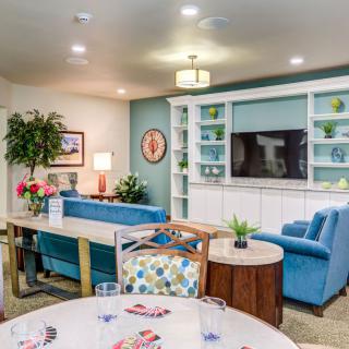 A cozy living room with a blue sofa, built-in shelves, and decorative plants.