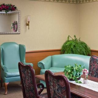 A conference room with a large table, upholstered chairs, a green sofa, and indoor plants.