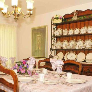 An elegant dining room with a table set for a meal, featuring a china cabinet and chandelier.