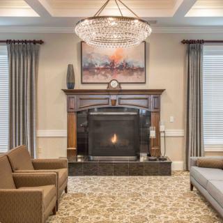 A luxurious living room featuring a central fireplace, elegant chandelier, and tasteful artwork.