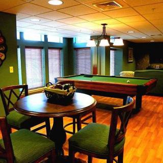 A cozy game room featuring a pool table and wooden furniture, accented by warm lighting.