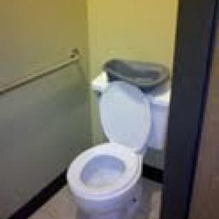 A small bathroom with a toilet and an open toilet seat.