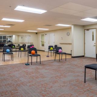 A spacious gym room with chairs set up for an exercise class, each holding a fitness ball.