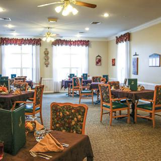 A well-lit dining room with several tables and chairs, decorated in a cozy style.