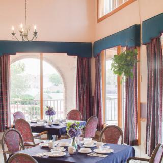A well-lit dining room with neatly set tables and large windows.