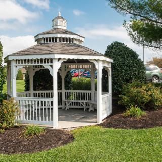 A picturesque white gazebo surrounded by lush green grass and shrubs.
