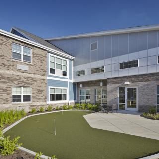 A modern building with a small landscaped outdoor area featuring artificial grass.