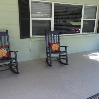 A cozy porch with two rocking chairs adorned with colorful cushions.