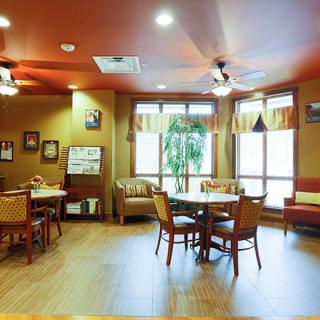 A cozy lounge area with tables and chairs, featuring large windows and tasteful decor.