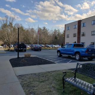 A view of a parking lot with a blue truck, surrounded by buildings and a cloudy sky.