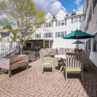 A sunny patio area with outdoor seating and umbrellas beside a white building.