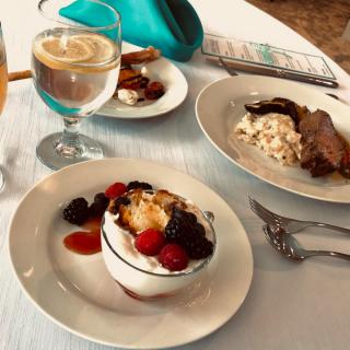 A table set with a dessert topped with berries, a savory dish, and a cappuccino.