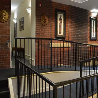 A modern interior featuring a ramp and railings against a brick wall, adorned with framed artwork and warm lighting.