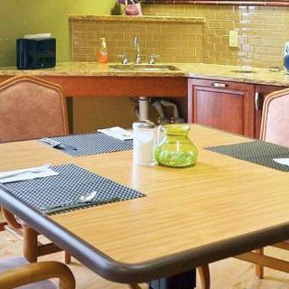 A cozy kitchen space with a dining table set for four, featuring placemats and a decorative glass jar.