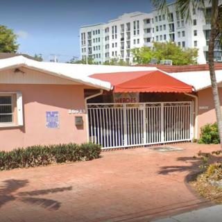 A small residential building with a gated entrance and brick driveway in an urban area.