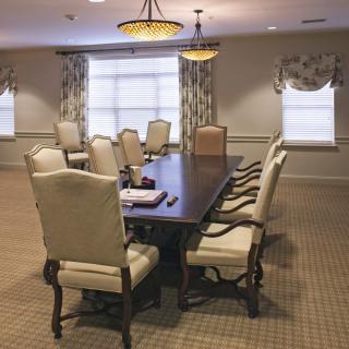 A well-furnished conference room with a large meeting table surrounded by chairs.