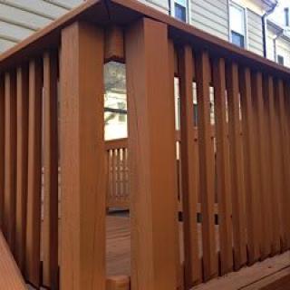 A wooden deck with vertical railings attached to a house.
