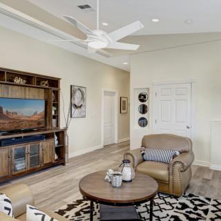 A modern living room featuring a large TV cabinet, comfortable armchair, and a stylish coffee table with decorative items.