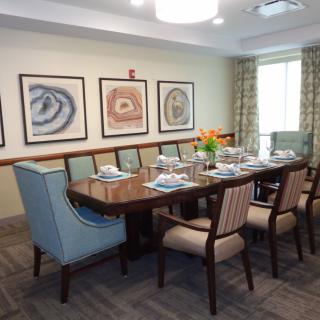 A formal dining room setup with a large table, chairs, and decorative artwork on the walls.