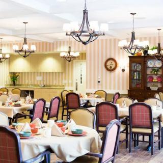 A well-decorated dining room with multiple tables and elegant chandeliers.