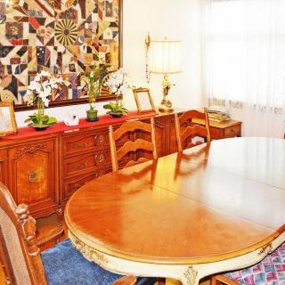 A cozy dining room with elegant wooden furniture and decorative quilt art on the wall.
