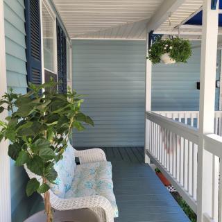 A cozy porch with a white bench, a potted plant, and a hanging plant.