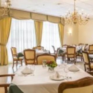 An elegant dining room with chandeliers, drapes, and a neatly set table.